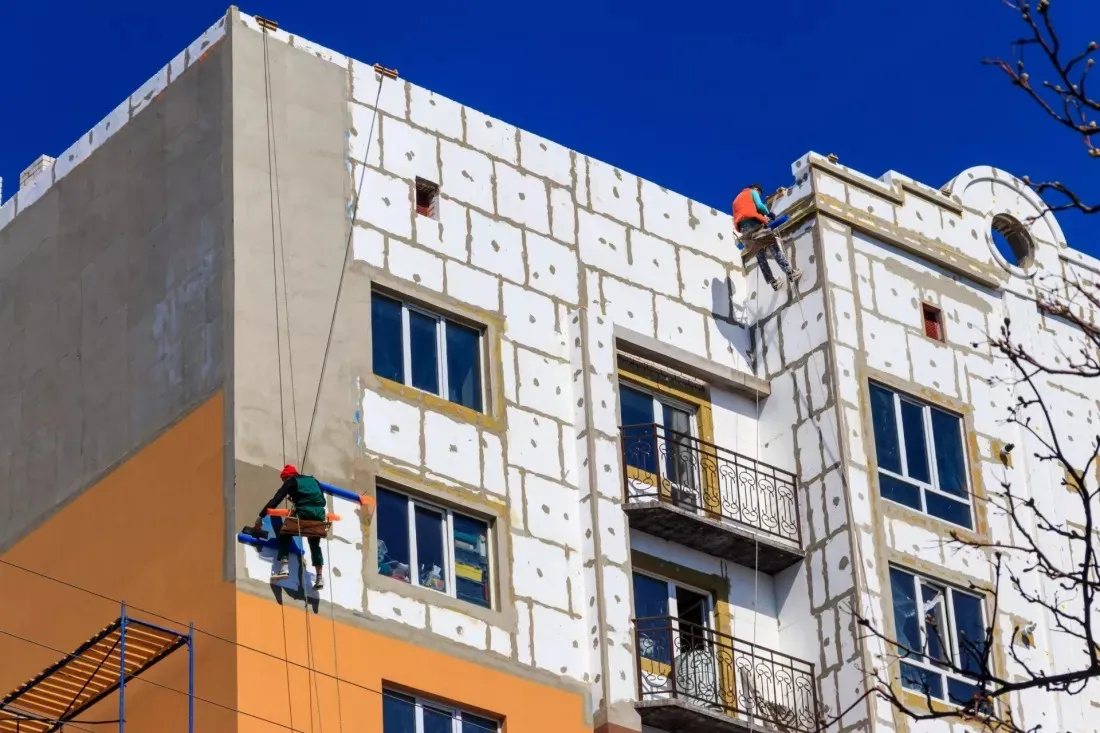 Operai isolano la facciata di un vecchio condominio